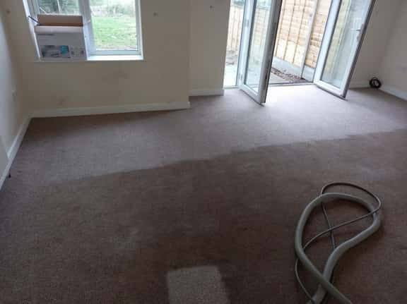 This is a photo of an empty living room with a brown carpet that is in the process of having its carpets steam cleaned works carried out by Chessington Carpet Cleaning