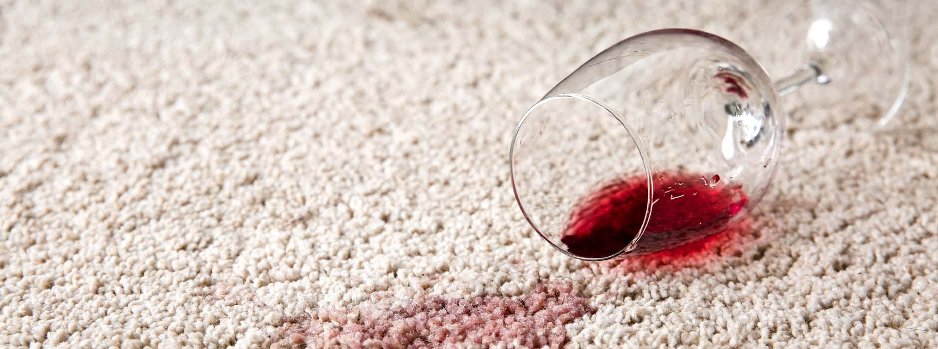 This is a photo of Chessington Carpet Cleaning red wine which has been spilt on a cream carpet. The glass is on its side.