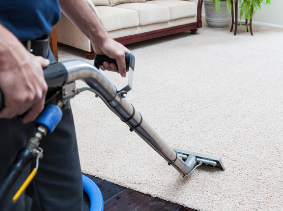 This is a photo of a man with a steam cleaner cleaning a cream carpet works carried out by Chessington Carpet Cleaning